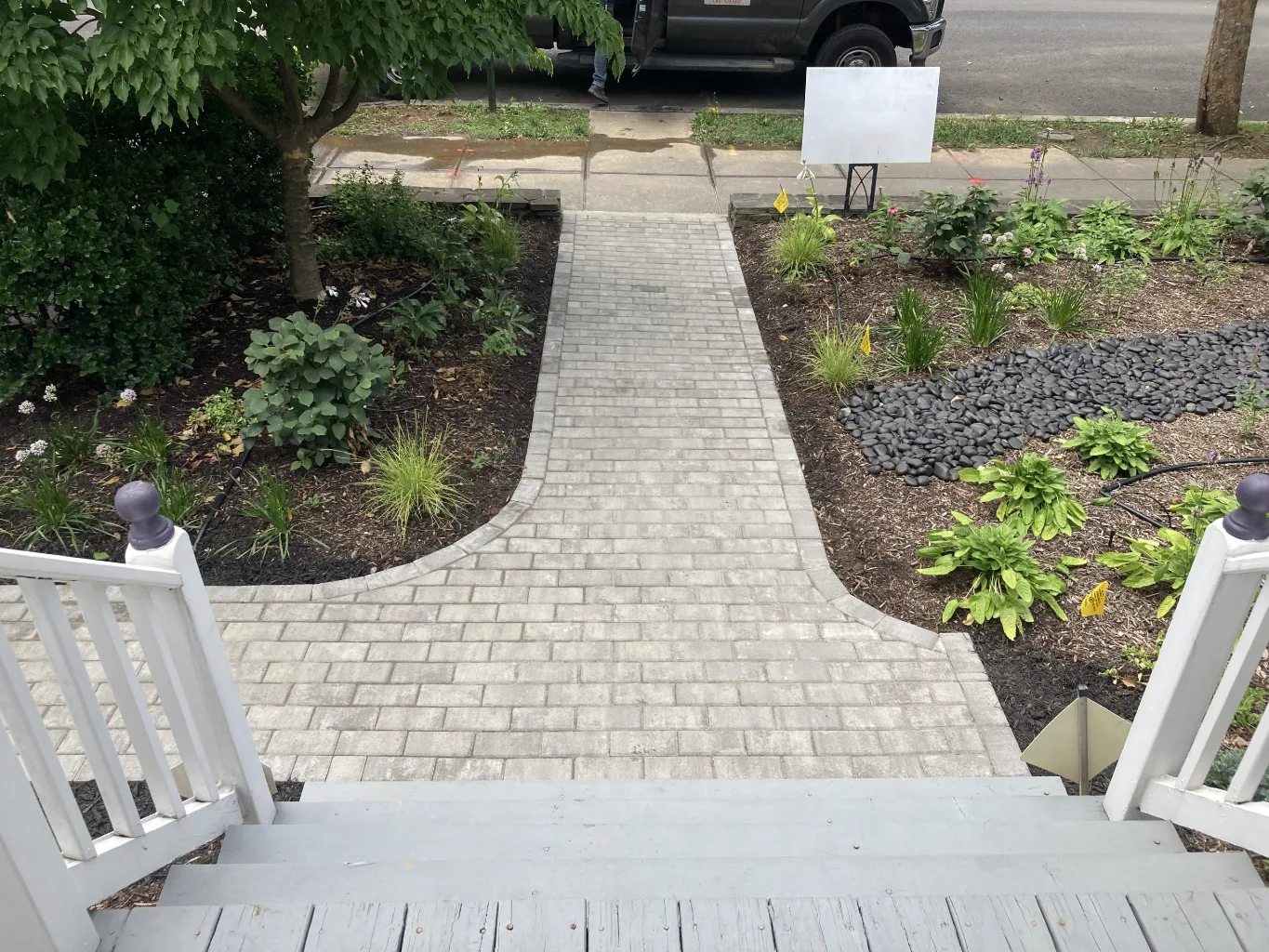 At the final compaction stage of a paver patio, a worker guides a plate compactor across the newly laid surface to settle the pavers and joint material