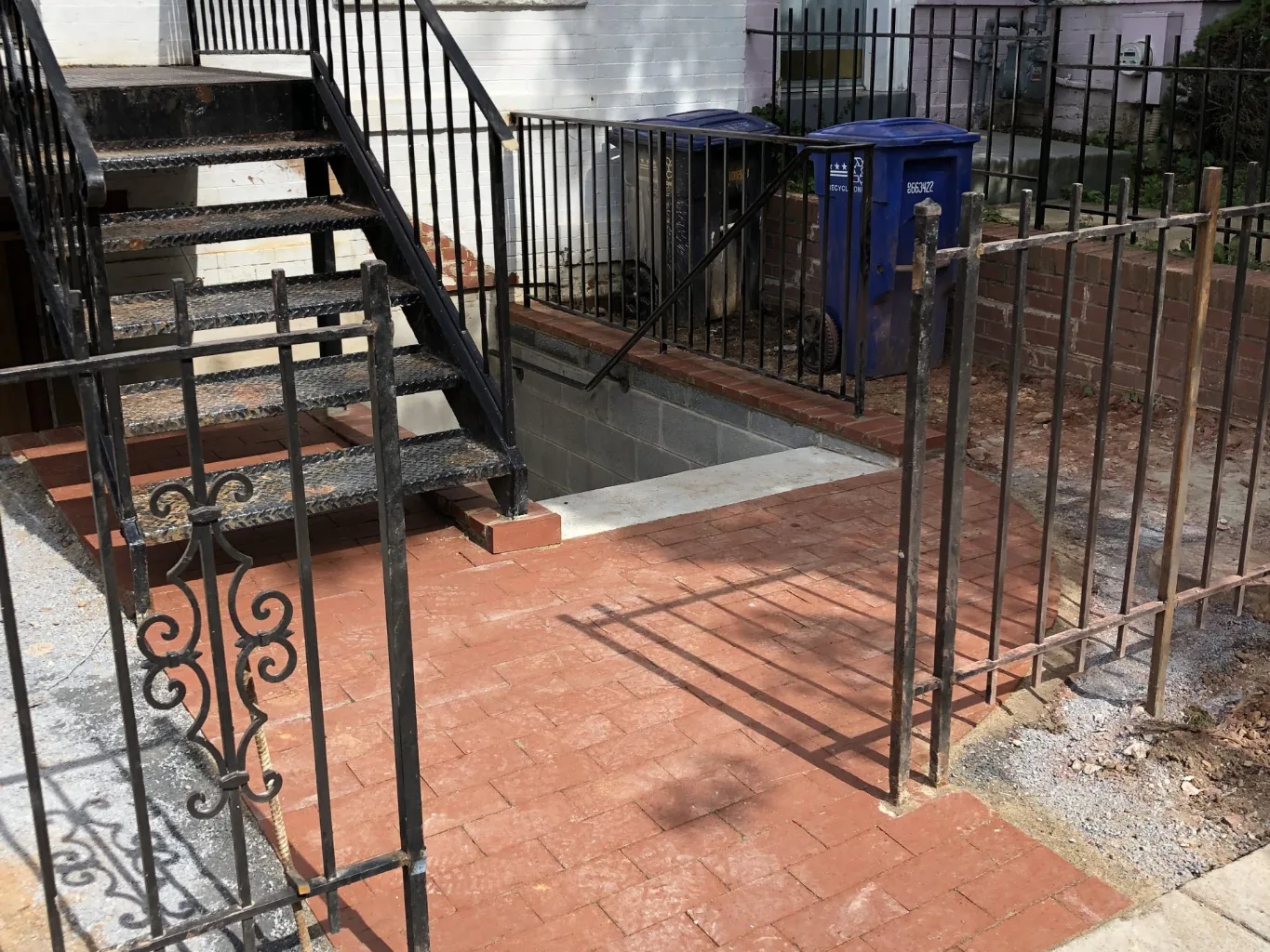 At the installation stage of a paver walkway, a worker taps an individual paver into place with a rubber mallet and checks its alignment with a spirit level